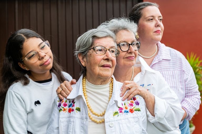 Four women of different ages sharing a heartfelt moment outdoors.